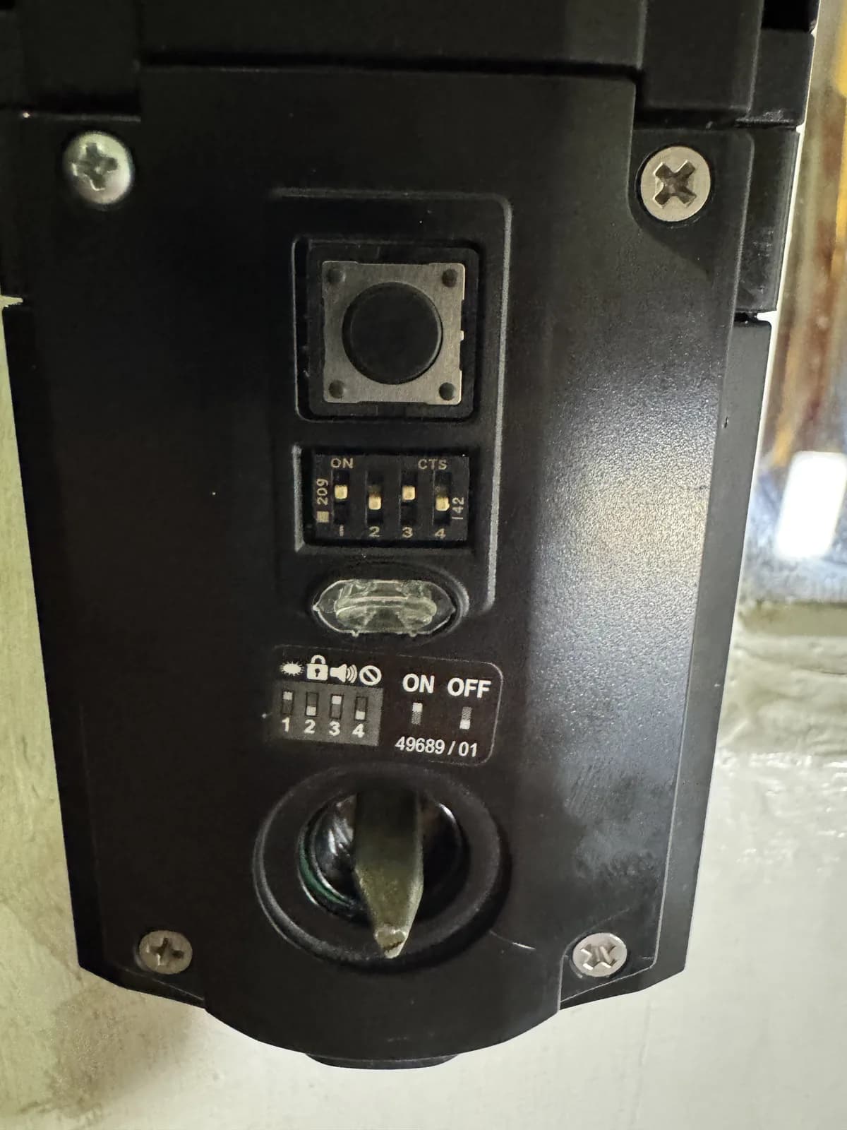 Configuration switches inside a commercial exit-door alarm during an on-site service call